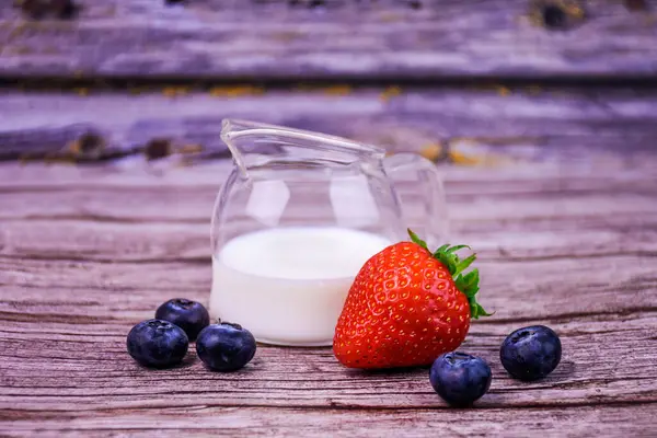 Taze böğürtlen ve süt. Kırsal ahşap arka planda cam sürahi.