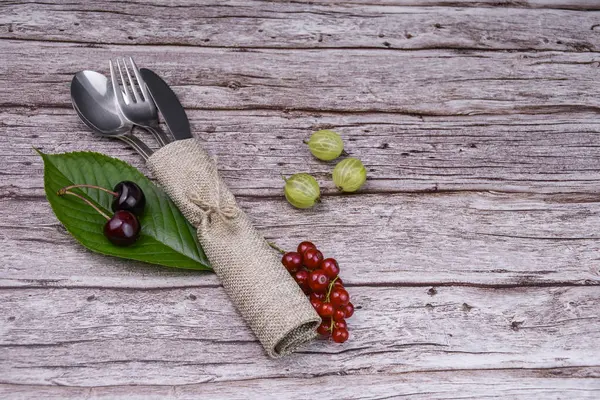 Ahşap masada böğürtlen ve yaprak ile kırsal çatal bıçak takımı.