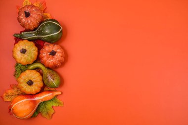 Sonbahar arkaplanı dekoratif balkabakları, renkli yapraklar ve turuncu arkaplan üzerine yerleştirilmiş doğal dokular..