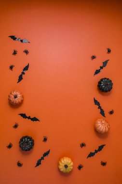 Parlak turuncu bir zemin üzerinde balkabakları, yarasalar ve örümceklerle Cadılar Bayramı kompozisyonu.