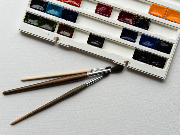 кисть в руке с черным рукавом на белом фоне холста