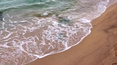 Bulutlu havada kumlu sahil boyunca deniz dalgaları. Yüksek kaliteli FullHD görüntüler