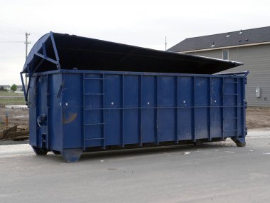 İnşaat halindeki yeni dubleks evlerin önündeki büyük mavi konteynır..