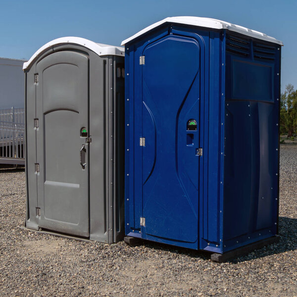 Two porta potty toilets outside near raceway.