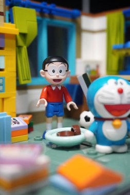 Odasındaki eşyalar arasında Japon oyuncak figürleri (Nobita ve Doraemon) yer alıyor