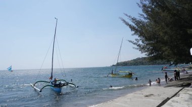 Situbondo 'nun Beyaz Kum Sahili' ne gelen ziyaretçiler gün boyunca sahilde oynuyorlar.