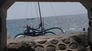 A traditional boat that is leaning on the beach of Pasir Putih Situbondo during the day in a frame