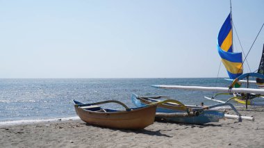 Two traditional boats placed on the beach facing the sea during the day with leaves on it at the Pasir Putih beach area of Situbondo