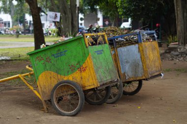 Parkta çöplerle dolu pis görünümlü bir çöp arabası.