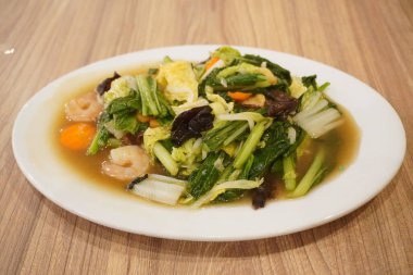 Bir restoranda hardal yeşili, mantar, havuç ve diğer sağlıklı yiyecekleri içeren Capcay yemeği