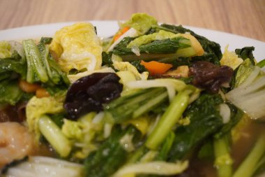 Bir restoranda hardal yeşili, mantar, havuç ve diğer sağlıklı yiyecekleri içeren Capcay yemeği