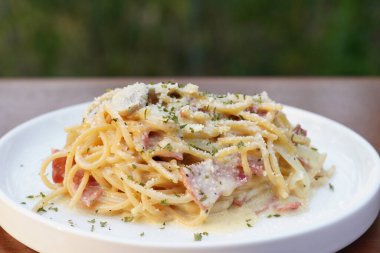 Beyaz yuvarlak bir tabakta servis edilen spagetti tabanlı makarna hazırlama servisi çekici bir görünüme ve bulanık bir arka plana sahip.