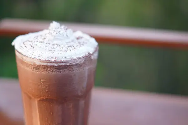 stock image Iced chocolate drink served in a clear glass with white cream and chocolate powder on top