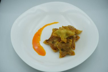 Beyaz bir tabakta kırmızı biberli kızarmış hamur köftesi.