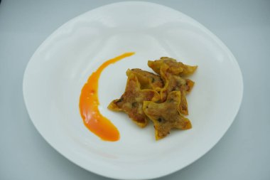 Beyaz bir tabakta kırmızı biberli kızarmış hamur köftesi.