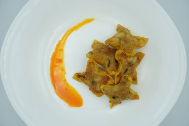 Beyaz bir tabakta kırmızı biberli kızarmış hamur köftesi.