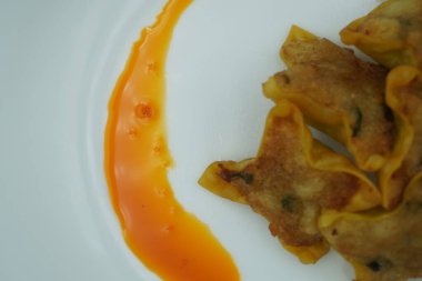 Beyaz bir tabakta kırmızı biberli kızarmış hamur köftesi.