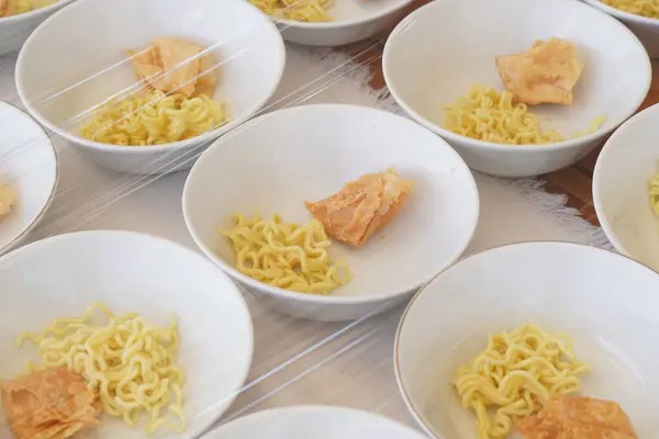 stock image Several white bowls containing yellow noodles, fried foods and meatballs without sauce on the table