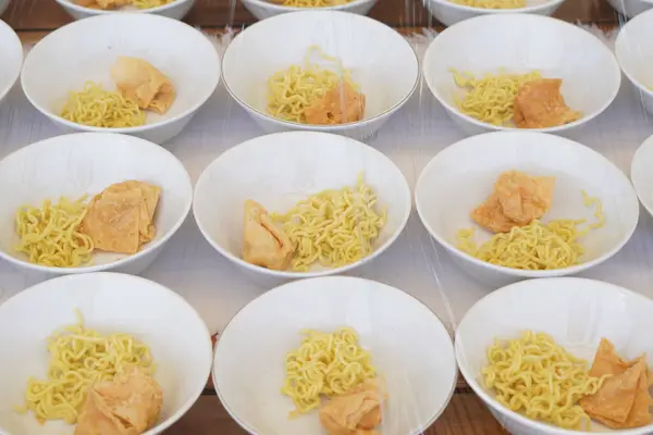 stock image Several white bowls containing yellow noodles, fried foods and meatballs without sauce on the table