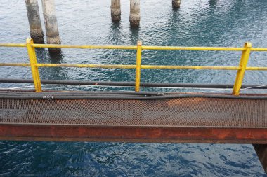 Demir köprü ve deniz suyu üzerinde sarı korkuluklar.