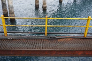 Demir köprü ve deniz suyu üzerinde sarı korkuluklar.