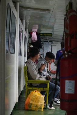 Feribot yolcuları teknenin içinde oturuyor.