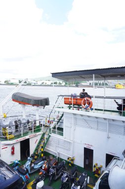 Geminin dışında oturan feribot yolcuları sabah deniz manzarasına bakarlar.