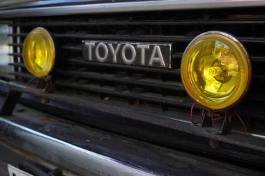 Toyota harfleri tozlu, 1980 model sarı ışıklı Corolla DX 'in önünde.