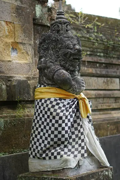 Bali 'den gelen taş oyma heykel siyah beyaz bir Balili damalı sarong giyiyor.