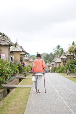 Penglipuran köyü Bali 'de elinde sopayla gezen yaşlı bir adam.