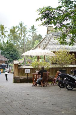 Penglipuran köyü, Bali 'de park alanını koruyan bir adam oturuyor.