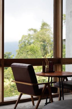 Kintamani, Bali manzarasını görmek için büyük şeffaf camların yanındaki estetik kafede masa ve sandalyeler.