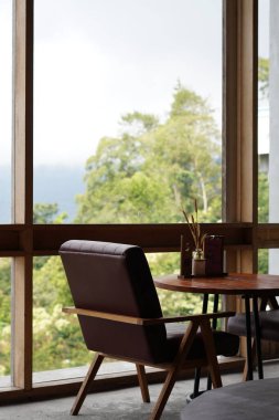 Kintamani, Bali manzarasını görmek için büyük şeffaf camların yanındaki estetik kafede masa ve sandalyeler.