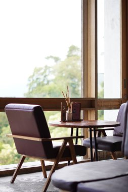 Kintamani, Bali manzarasını görmek için büyük şeffaf camların yanındaki estetik kafede masa ve sandalyeler.