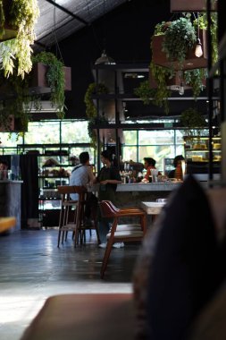 Estetik bir kafeye gelen ziyaretçiler bir masada oturmuş içki ısmarlıyorlar.