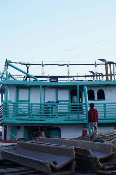 stock image A man working at the Benoa harbor with a ship docked in the afternoon