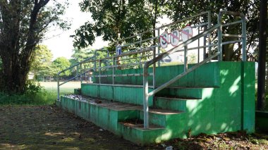 Adımları, trafik parkındaki Singha Park Malang ziyaretçilerinin yanında oturmak için kullanılabilecek küçük yeşil bir tezgah.