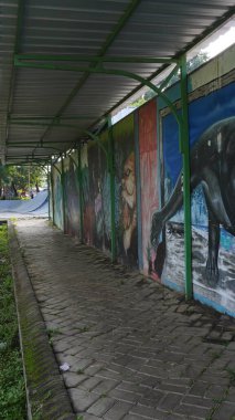 The sidewalk at Singha Park Malang in the morning with various kinds of murals on the walls clipart