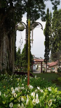 A garden lamp that looks worn out with one bulb missing and a rusty pole in a tourist area clipart