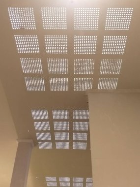 The ceiling of a building with a checkered pattern of holes for light to enter. clipart