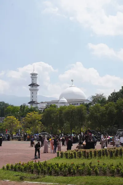 stock image The helipad at Muhammadiyah University of Malang during the day is crowded with graduates gathering with a background of a mosque, trees and bright sky