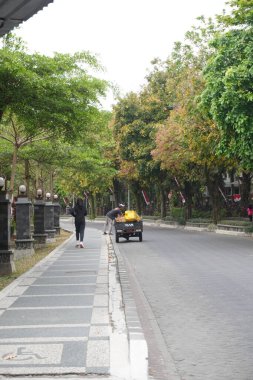 A three-wheeled motorbike stopped at the side of a quiet road in the morning clipart