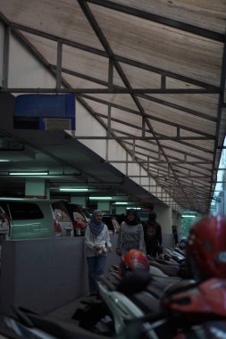 Bir alışveriş merkezinde motosiklet parkı ve yanından geçen ziyaretçiler.
