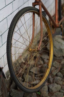 Beyaz tuğlalı bir duvara yaslanmış antik altın bisiklet tekerlekleri ve kaldırımlı bir sokak