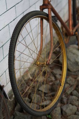 Beyaz tuğlalı bir duvara yaslanmış antik altın bisiklet tekerlekleri ve kaldırımlı bir sokak