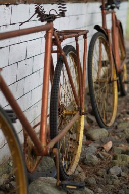 Beyaz tuğlalı bir duvara yaslanmış antik altın bisiklet tekerlekleri ve kaldırımlı bir sokak