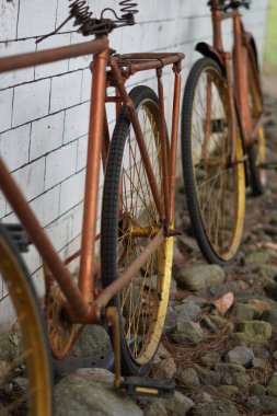 Beyaz tuğlalı bir duvara yaslanmış antik altın bisiklet tekerlekleri ve kaldırımlı bir sokak