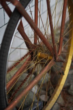 Beyaz tuğlalı bir duvara yaslanmış antik altın bisiklet tekerlekleri ve kaldırımlı bir sokak