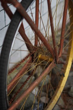 Beyaz tuğlalı bir duvara yaslanmış antik altın bisiklet tekerlekleri ve kaldırımlı bir sokak