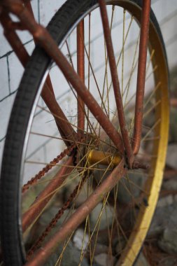 Beyaz tuğlalı bir duvara yaslanmış antik altın bisiklet tekerlekleri ve kaldırımlı bir sokak